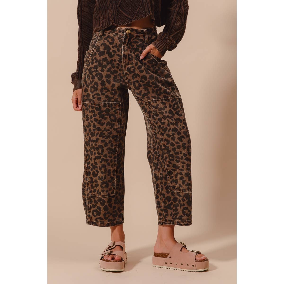 Person wearing leopard print pants and brown sandals on a beige background
